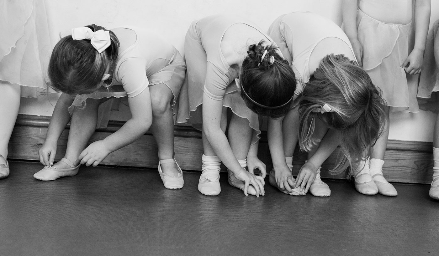 Young ballet students tying their ballet shoes